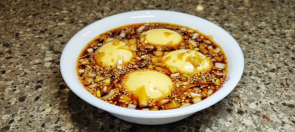 Korean soy marinated eggs with scallions and sesame seeds in a soy sauce marinade