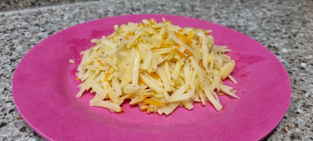 Korean shredded potato stir-fry with carrots served on a pink plate